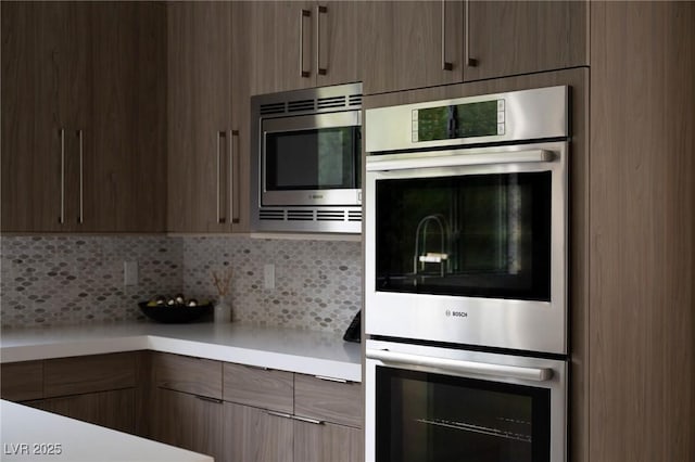 kitchen with light countertops, backsplash, stainless steel appliances, and modern cabinets