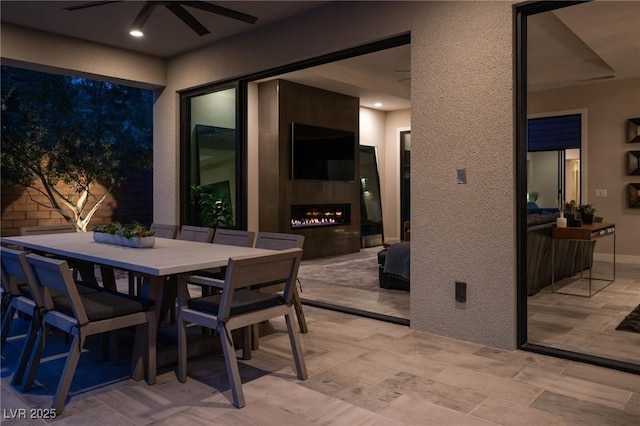 view of patio featuring outdoor dining space, a large fireplace, and ceiling fan