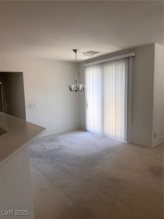 unfurnished dining area with light colored carpet, a chandelier, and visible vents