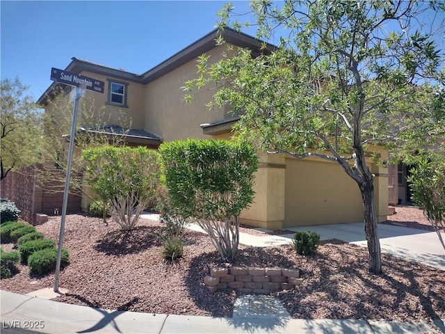 view of front of house with stucco siding, concrete driveway, and an attached garage