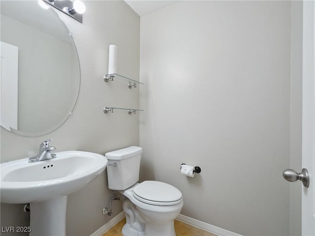half bathroom featuring toilet, baseboards, and a sink