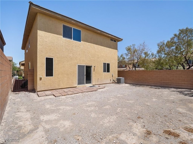 rear view of house featuring stucco siding, a fenced backyard, and central air condition unit