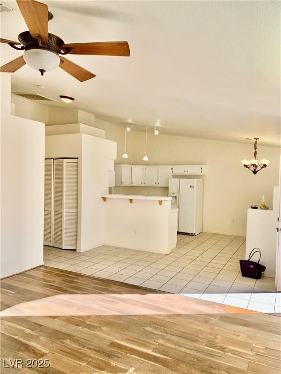 unfurnished living room with ceiling fan with notable chandelier and light tile patterned floors