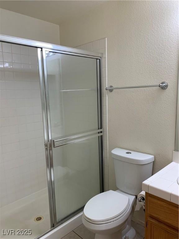 bathroom with vanity, a shower stall, and toilet