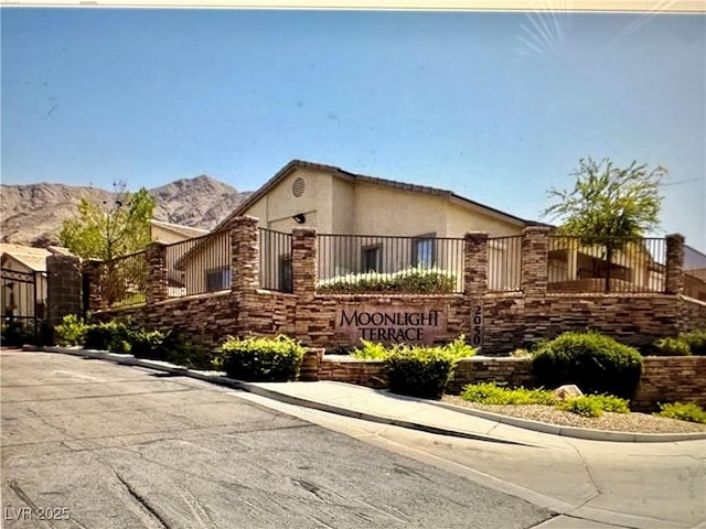 ranch-style house with fence, a mountain view, and stucco siding