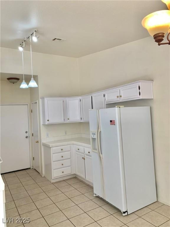kitchen with white cabinets, visible vents, track lighting, white fridge with ice dispenser, and light tile patterned floors