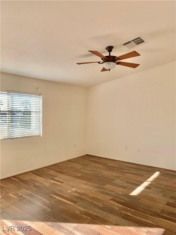 spare room with wood finished floors, visible vents, and a ceiling fan