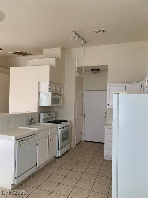 kitchen featuring white cabinets, visible vents, a sink, and white appliances