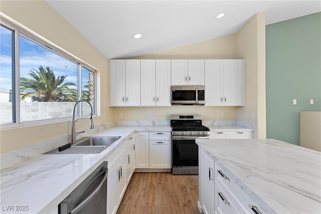 7957 Lovely Pine Pl, Las Vegas, NV 89143 - kitchen with appliances with stainless steel finishes, lofted ceiling, white cabinetry, light wood-style flooring, and light stone counters