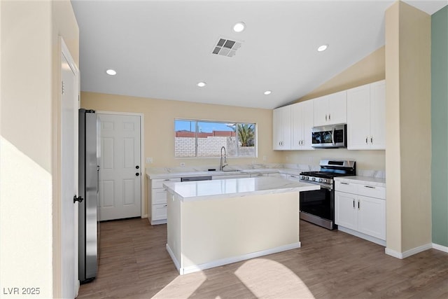 7957 Lovely Pine Pl, Las Vegas, NV 89143 - kitchen with appliances with stainless steel finishes, light countertops, white cabinets, light wood-style flooring, and a kitchen island