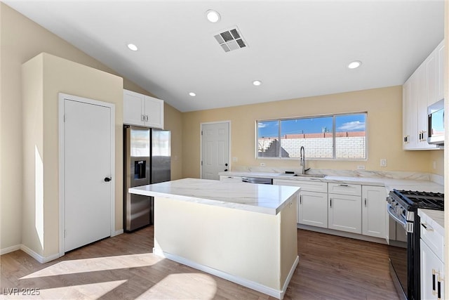 7957 Lovely Pine Pl, Las Vegas, NV 89143 - kitchen featuring stainless steel appliances, wood finished floors, white cabinetry, a kitchen island, and lofted ceiling