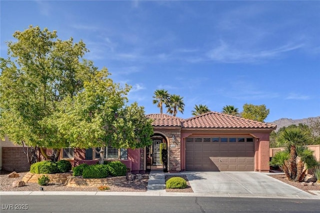mediterranean / spanish home with stucco siding, an attached garage, a tiled roof, and concrete driveway