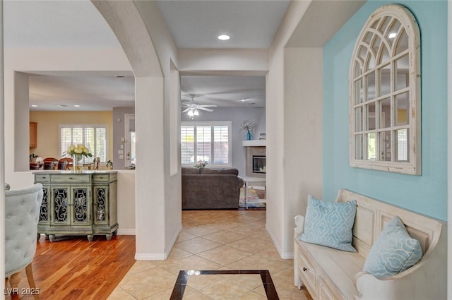 hallway with arched walkways, plenty of natural light, baseboards, and recessed lighting