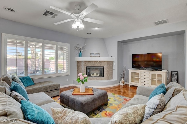 living room with wood finished floors, visible vents, a ceiling fan, and baseboards
