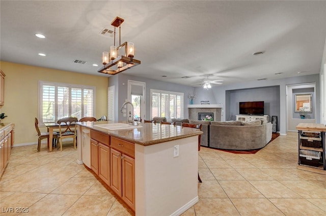 kitchen featuring a glass covered fireplace, visible vents, a sink, and light tile patterned floors