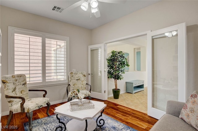 living area featuring baseboards, a ceiling fan, wood finished floors, and visible vents
