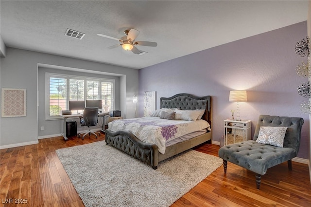 bedroom with ceiling fan, baseboards, wood finished floors, and visible vents