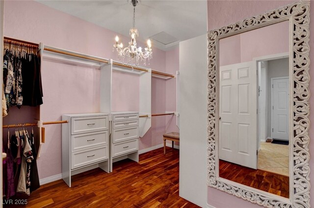 walk in closet with a notable chandelier and dark wood-style flooring