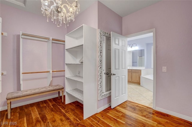 walk in closet featuring light wood finished floors and an inviting chandelier