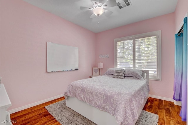 bedroom with wood finished floors, visible vents, baseboards, and ceiling fan