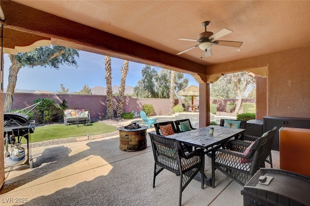 view of patio / terrace with a fenced backyard, a fire pit, a ceiling fan, outdoor dining area, and area for grilling
