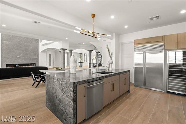 kitchen with a sink, open floor plan, decorative columns, visible vents, and appliances with stainless steel finishes