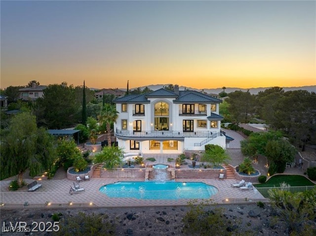 back of house featuring a tiled roof, a patio area, stairs, a balcony, and a pool with connected hot tub