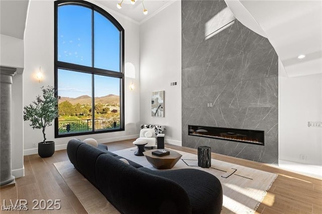 living room featuring recessed lighting, a high ceiling, wood finished floors, baseboards, and a tiled fireplace