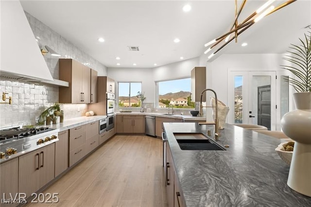 kitchen featuring backsplash, visible vents, a sink, appliances with stainless steel finishes, and custom exhaust hood