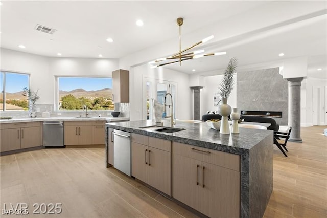 kitchen featuring dishwasher, a center island with sink, a sink, and visible vents