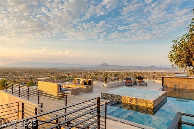 view of pool featuring a pool with connected hot tub, an outdoor living space with a fire pit, and a mountain view