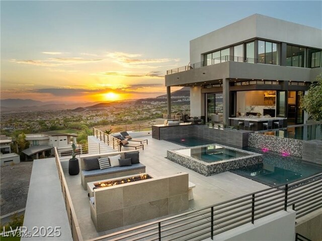 view of patio featuring a pool with connected hot tub, an outdoor living space with a fire pit, area for grilling, and a balcony