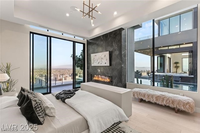 bedroom featuring a wall of windows, wood finished floors, access to outside, and a notable chandelier