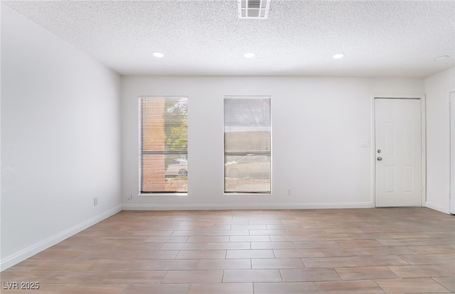 spare room featuring recessed lighting, a textured ceiling, visible vents, and baseboards