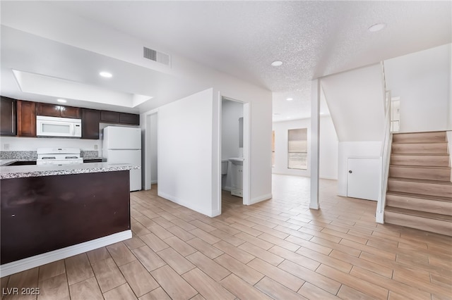 kitchen with a textured ceiling, dark brown cabinets, visible vents, recessed lighting, and white appliances
