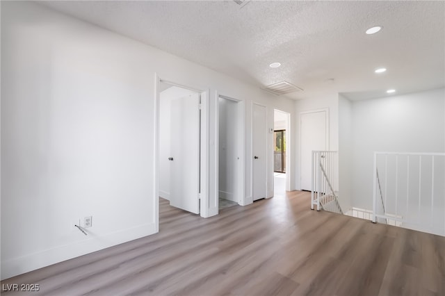 unfurnished room with baseboards, wood finished floors, a textured ceiling, and recessed lighting