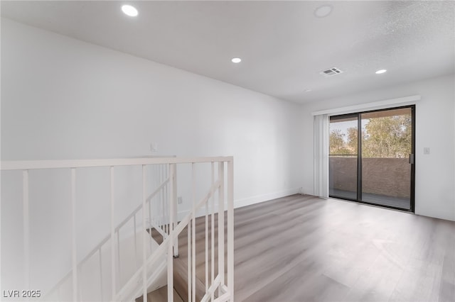 empty room featuring baseboards, wood finished floors, visible vents, and recessed lighting
