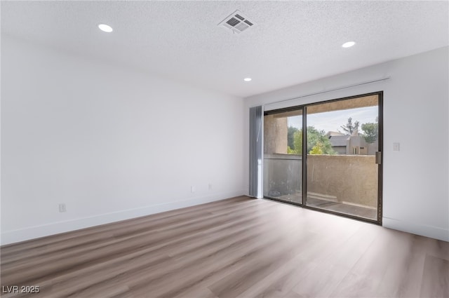 unfurnished room featuring recessed lighting, wood finished floors, a textured ceiling, and baseboards