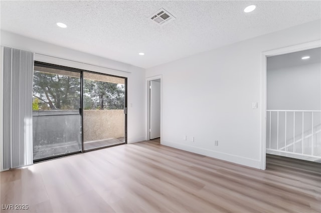 interior space featuring recessed lighting, a textured ceiling, wood finished floors, and visible vents