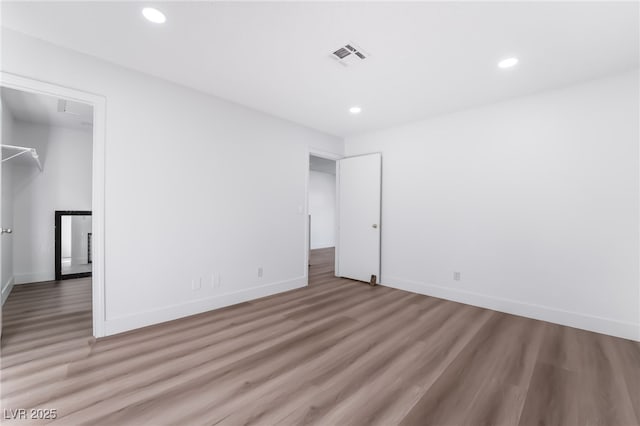 unfurnished bedroom with baseboards, wood finished floors, visible vents, and recessed lighting