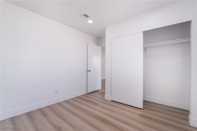 unfurnished bedroom featuring light wood-style flooring, baseboards, visible vents, recessed lighting, and a closet