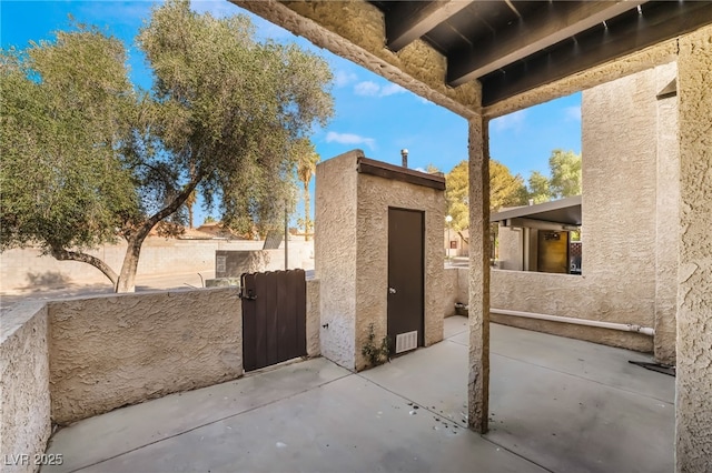 view of patio / terrace with fence, an outbuilding, a gate, and a storage shed