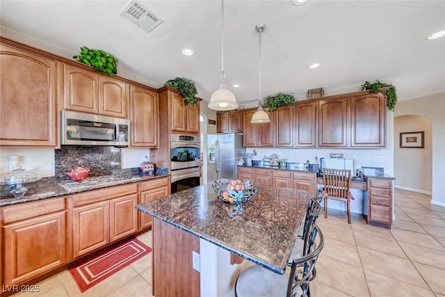 2733 Auchmull St, Henderson, NV 89044 - kitchen with appliances with stainless steel finishes, arched walkways, dark stone counters, light tile patterned floors, and recessed lighting