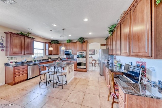 2733 Auchmull St, Henderson, NV 89044 - kitchen with appliances with stainless steel finishes, a breakfast bar area, arched walkways, a center island, and dark stone countertops