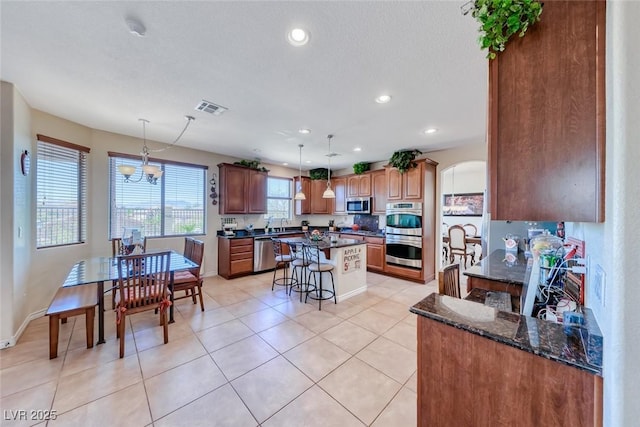 2733 Auchmull St, Henderson, NV 89044 - kitchen featuring stainless steel appliances, a kitchen breakfast bar, a kitchen island, a chandelier, and arched walkways