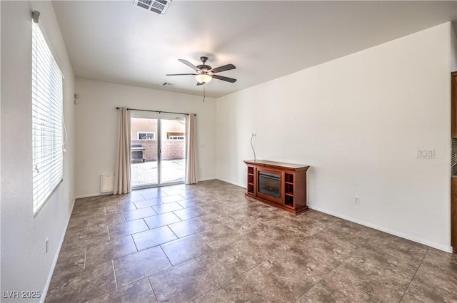 unfurnished living room with baseboards, a ceiling fan, a glass covered fireplace, and visible vents