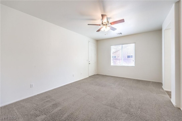 carpeted spare room featuring visible vents, baseboards, and ceiling fan