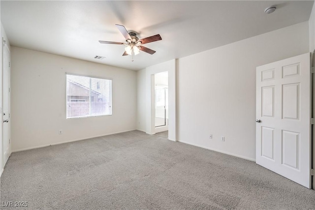 spare room with carpet floors, a ceiling fan, visible vents, and baseboards