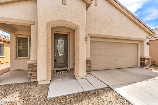 entrance to property featuring stucco siding, stone siding, and concrete driveway
