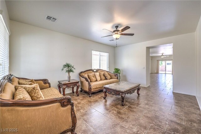 living area featuring baseboards, a ceiling fan, and visible vents